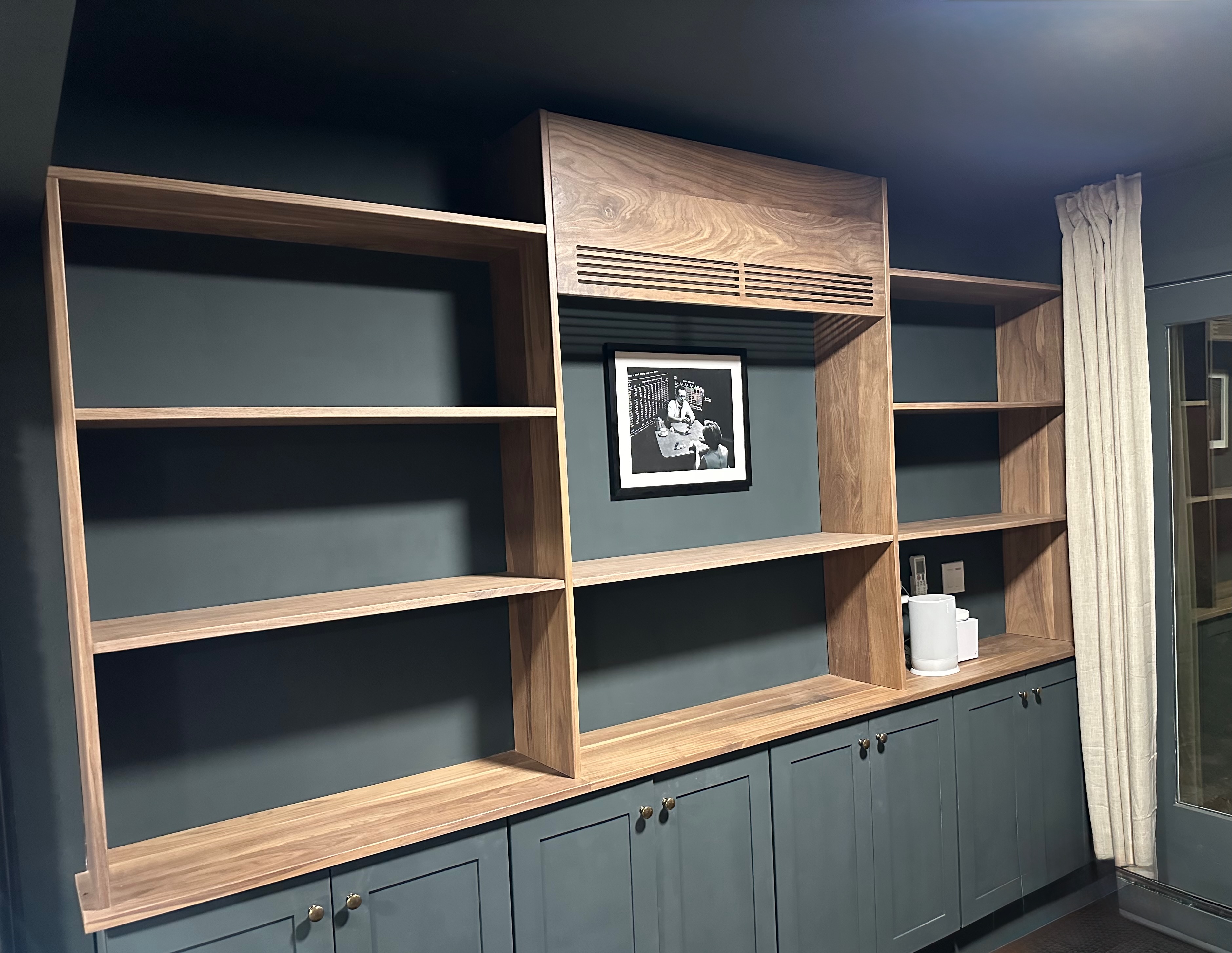 Built-in walnut shelving and cabinets against a deep navy wall